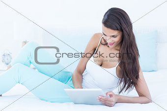 Beautiful woman using tablet pc on her bed