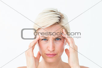 Pretty blonde suffering from headache looking at camera