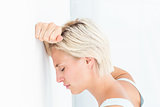 Sad blonde woman with her head on wall