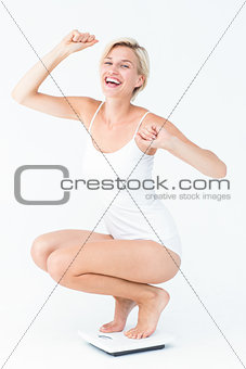 Happy attractive woman crouching on a scales