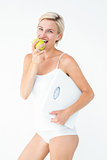 Happy woman holding scales eating apple