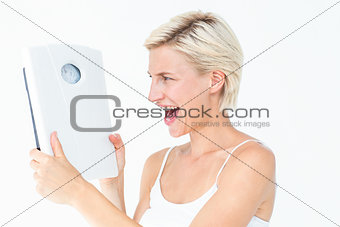 Happy blonde woman holding scales