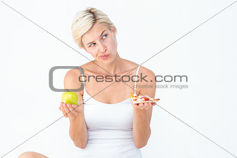 Pretty woman deciding between pizza and apple