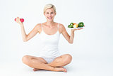 Attractive woman holding vegetables plate and dumbbell