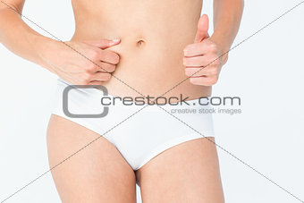 Woman with little fat on her belly with thumb up