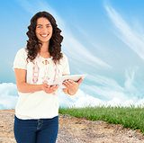 Composite image of smiling casual brunette using her tablet pc