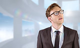 Composite image of young businessman thinking and looking up