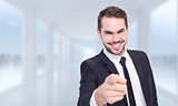 Composite image of happy businessman pointing at camera