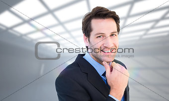 Composite image of businessman touching his chin while smiling at camera