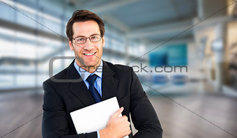 Composite image of smiling businessman holding his laptop looking at camera