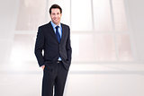 Composite image of smiling young businessman with hands in pockets