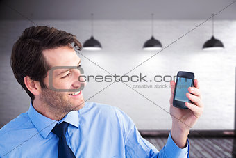 Composite image of smiling businessman showing smartphone to camera