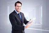 Composite image of businessman looking at the camera while using his tablet