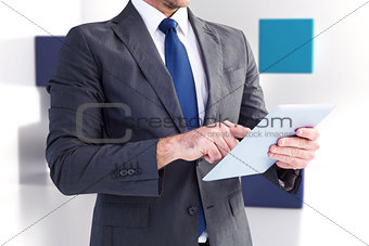 Composite image of businessman using his tablet pc