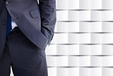 Composite image of businessman standing with hand in pocket