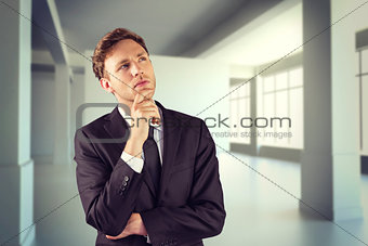 Composite image of young businessman thinking with hand on chin