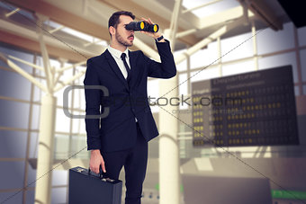 Composite image of businessman holding a briefcase while using binoculars