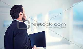 Composite image of businessman in suit holding laptop