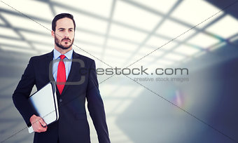 Composite image of handsome businessman holding briefcase and laptop
