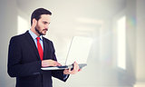 Composite image of focused businessman using his laptop