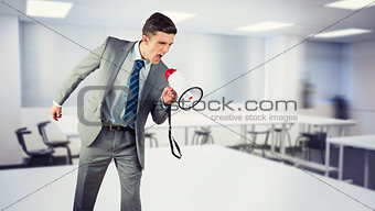Composite image of businessman shouting through megaphone