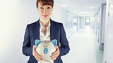 Composite image of businesswoman showing piggy bank