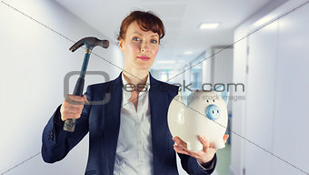 Composite image of businesswoman breaking piggy bank