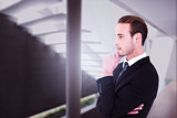 Composite image of thinking businessman standing with hand on chin