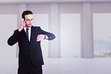 Composite image of serious businessman phoning while checking time