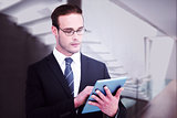 Composite image of unsmiling businessman using tablet pc
