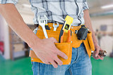 Composite image of cropped image of technician with tool belt around waist