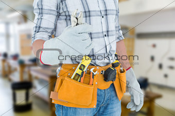 Composite image of technician with tool belt around waist holding pliers