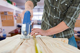 Composite image of carpenter cutting wooden plank with electric saw