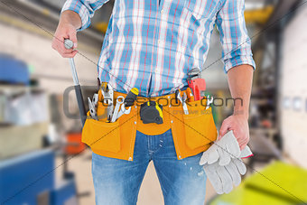 Composite image of midsection of handyman holding hammer and gloves