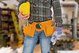 Composite image of manual worker wearing tool belt while holding gloves and helmet