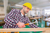 Composite image of handyman using hammer on wood