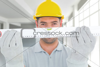 Composite image of portrait of handyman holding spirit level