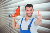Composite image of smiling repairman with drill machine gesturing thumbs up
