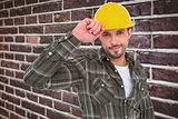 Composite image of smiling handyman holding helmet