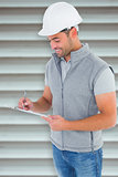 Composite image of smiling manual worker writing on clipboard