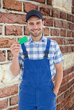 Composite image of smiling young repairman holding green card