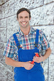 Composite image of confident plumber holding monkey wrench