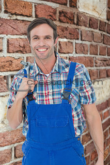 Composite image of confident plumber holding tool over white background