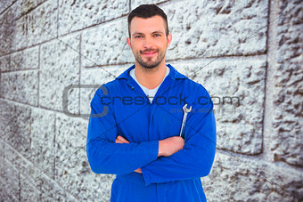 Composite image of happy mechanic holding spanner on white background