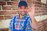 Composite image of portrait of smiling repairman gesturing okay