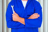 Composite image of male mechanic holding spanner on white background