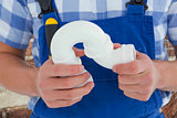 Composite image of plumber holding sink pipe on white background