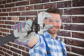 Composite image of handyman wearing protective glasses while holding wrench