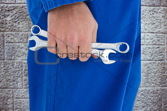 Composite image of male mechanic holding spanners