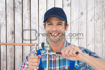 Composite image of portrait of happy plumber fixing pipe